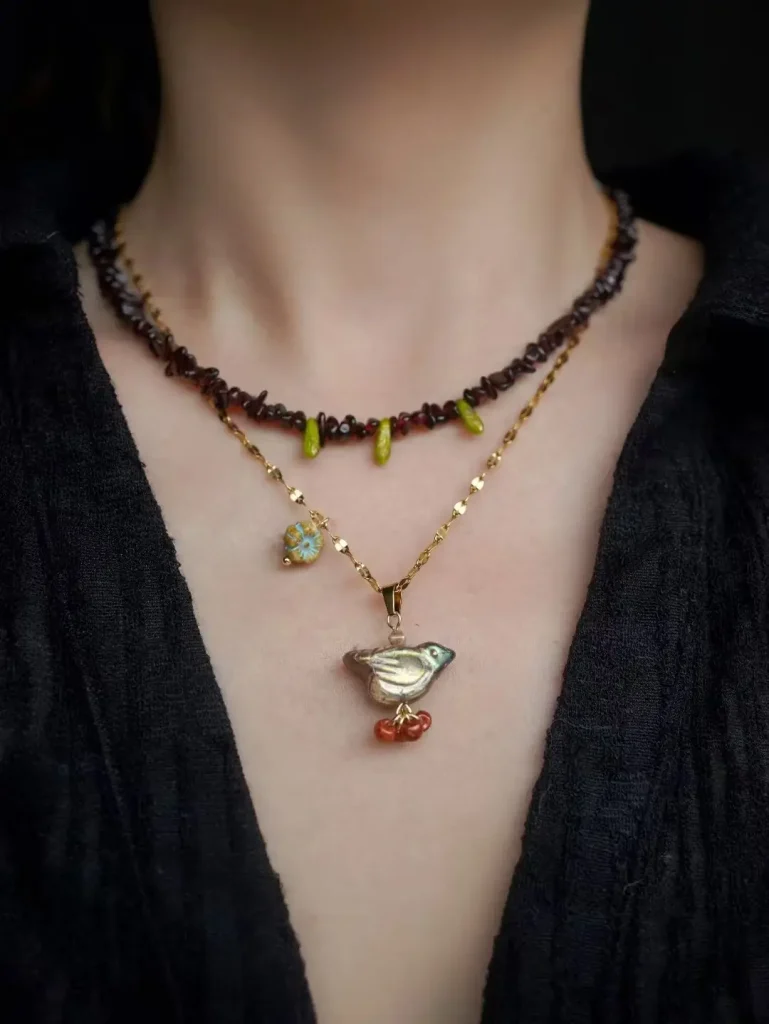 Garnet necklace with glass bird pendant on steel-titanium chain, inspired by the Thornbird story, part of PeonyJewels' vintage handmade earrings and jewelry collection