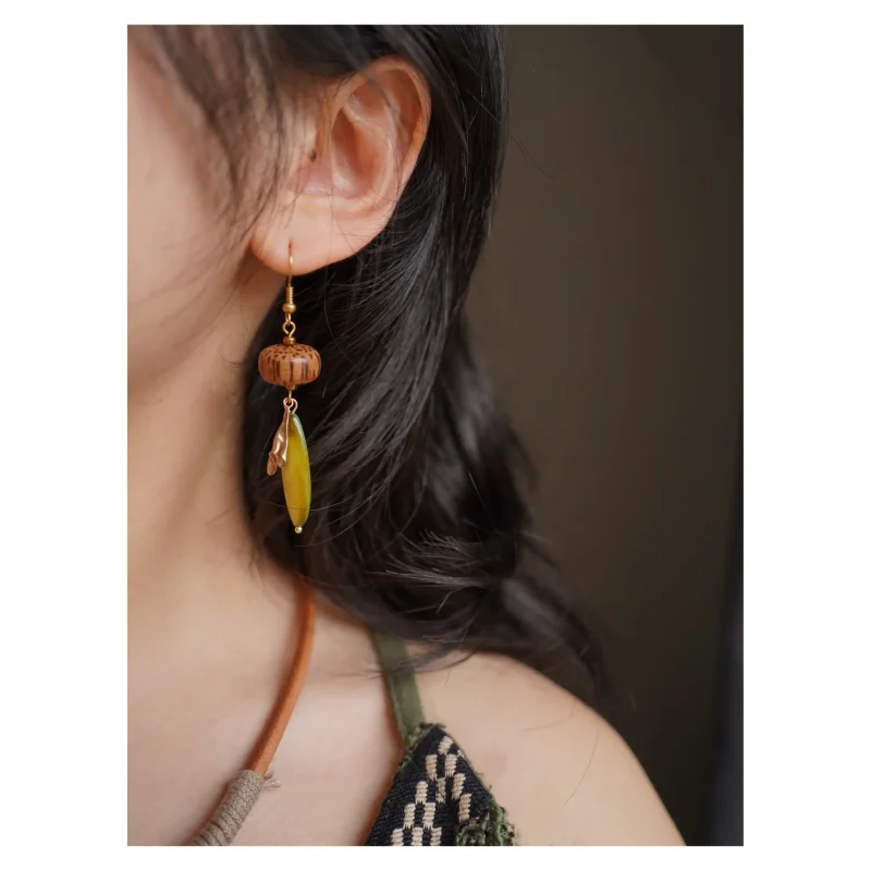 Model wears handmade green leaf dangle earrings, revealing vintage charm with natural elegance