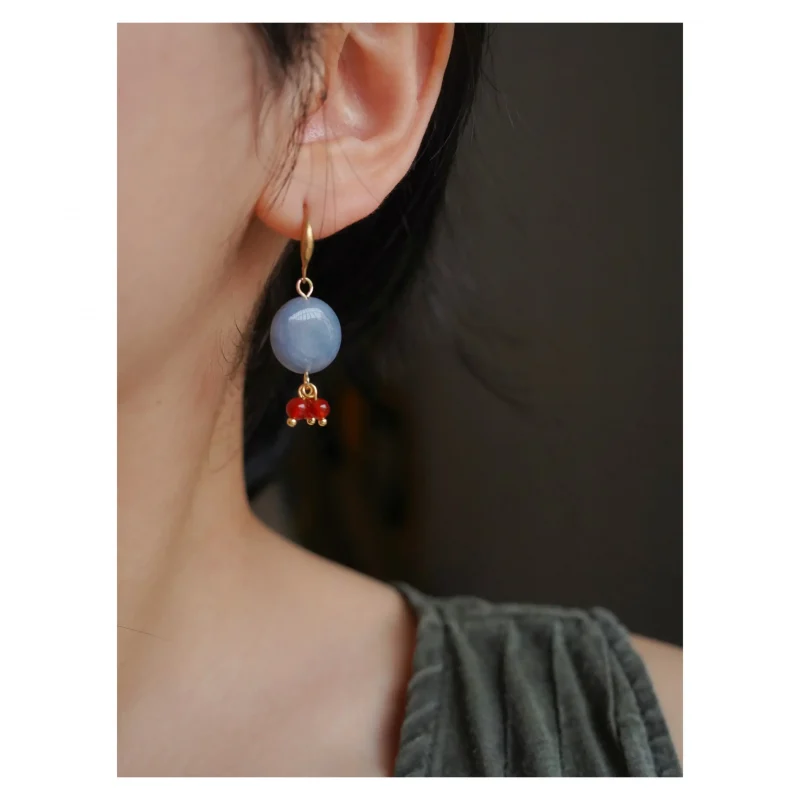 The model wears handcrafted vintage red agate earrings that highlight timeless elegance with artistic flair.