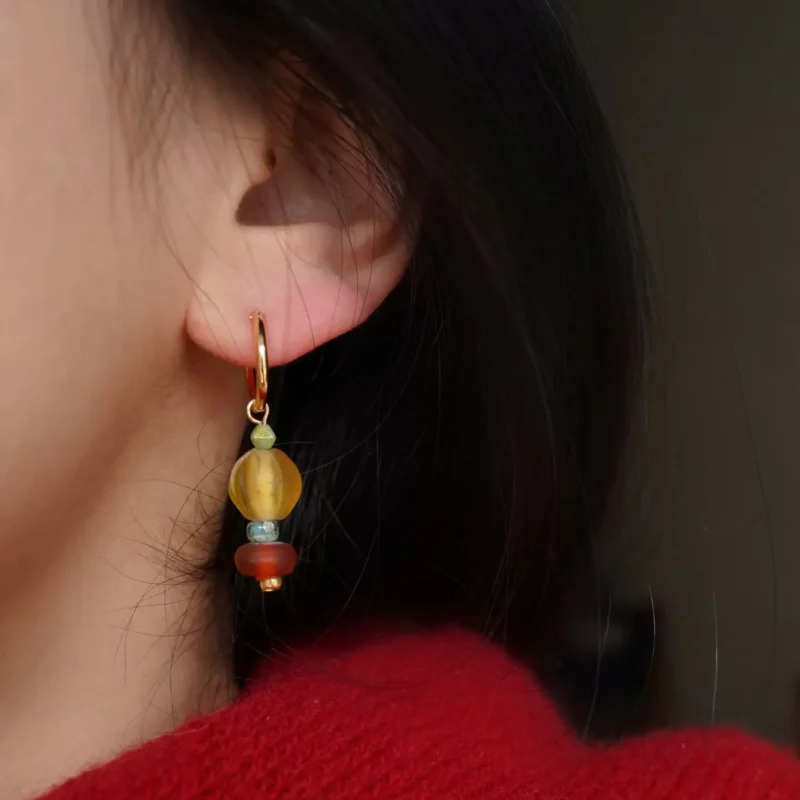 Model wearing glass bead hoop earrings with red and yellow agate, showcasing vintage handcrafted charm