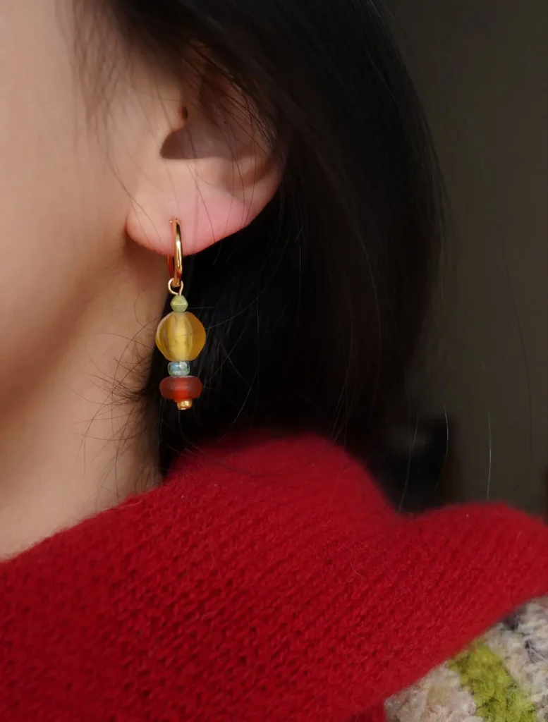 Model wearing colorful earrings, highlighting vibrant glass beads and a chic Bohemian-inspired style.