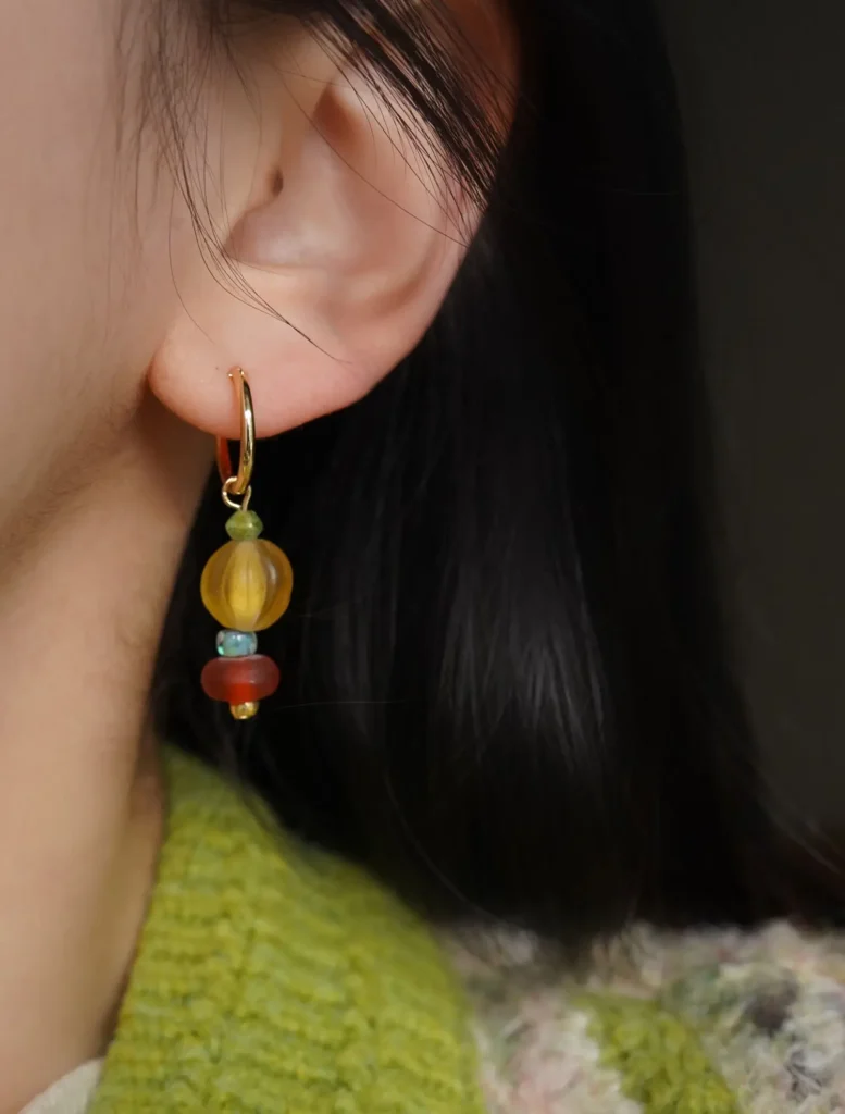Woman wearing beaded earrings, showcasing vibrant colors and artistic craftsmanship for a stylish daily look.