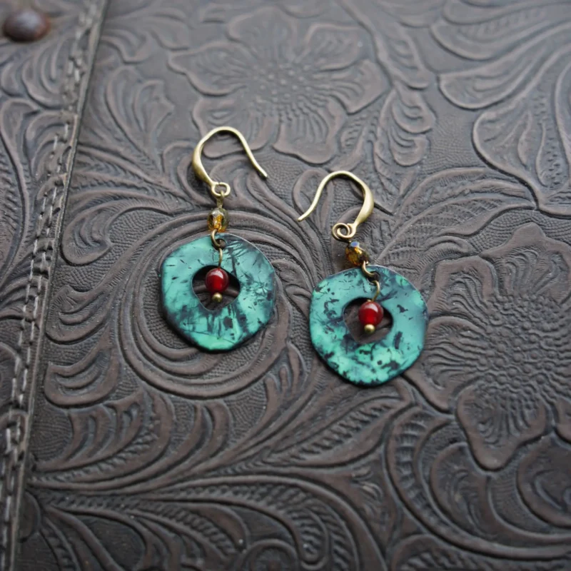 Artisans handcraft these round brass earrings with red agate to embody feminine strength.