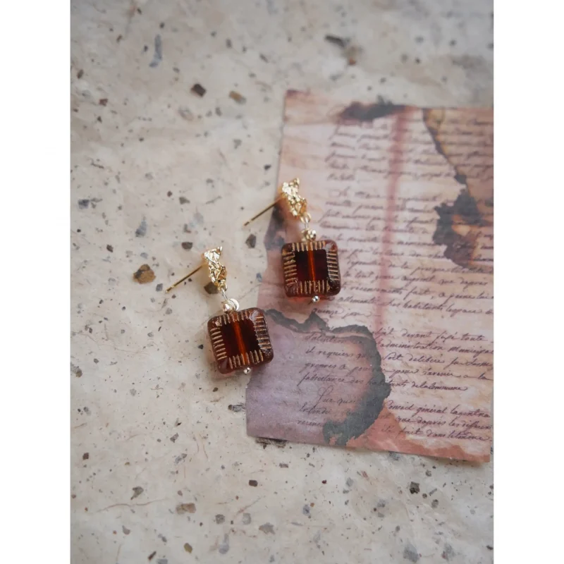 Handmade jewelry piece highlights a tea-colored glass pendant in a vintage Chinese-inspired design.