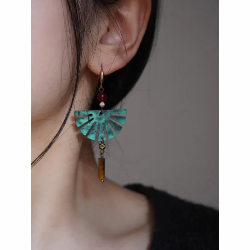 A woman wears handcrafted fan-shaped earrings that combine vintage charm with artisanal elegance.