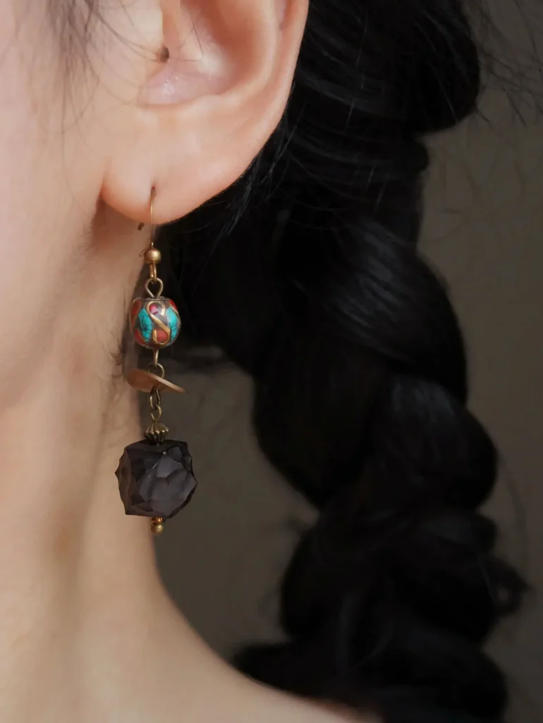 Close-up of a single Peonyjewels earring, featuring ebony wood with turquoise and agate inlays.
