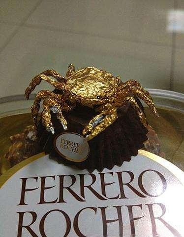 Crab-shaped jewelry piece with foil texture, shiny folds scatter light for a playful and sparkling effect.