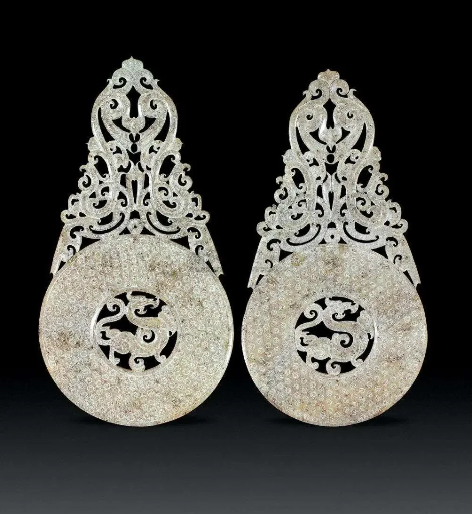 An image of a Han Dynasty jade bi disc with "out-of-the-rim" carving. The white jade features intricate carvings of dragons and phoenixes, extending beyond the main body of the disc. The jade is lustrous, and the craftsmanship is superb, reflecting the classic style of Han-era jade artifacts.