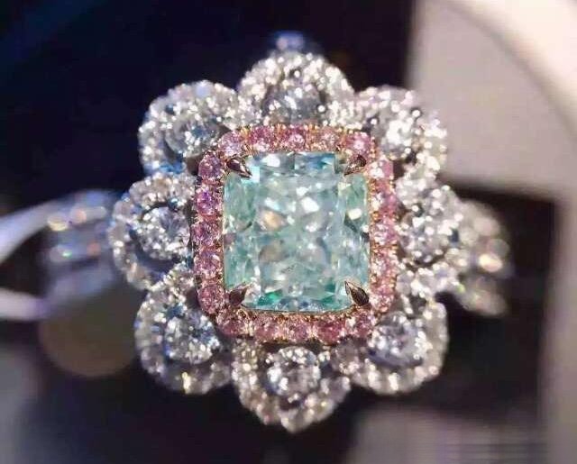 Light blue diamond ring accented with small pink diamonds, showing how pink side stones enhance the main stone's color and visual appeal.