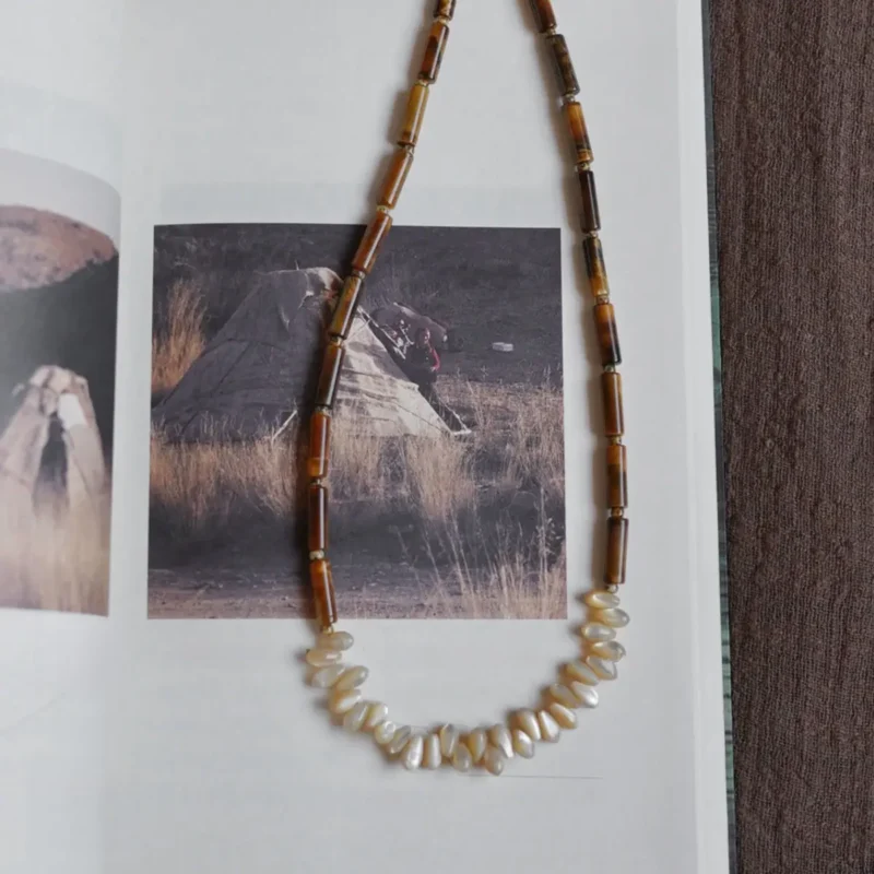 This natural tube-shaped tiger eye necklace features minimalist geometric lines and pairs elegantly with open-neck outfits.