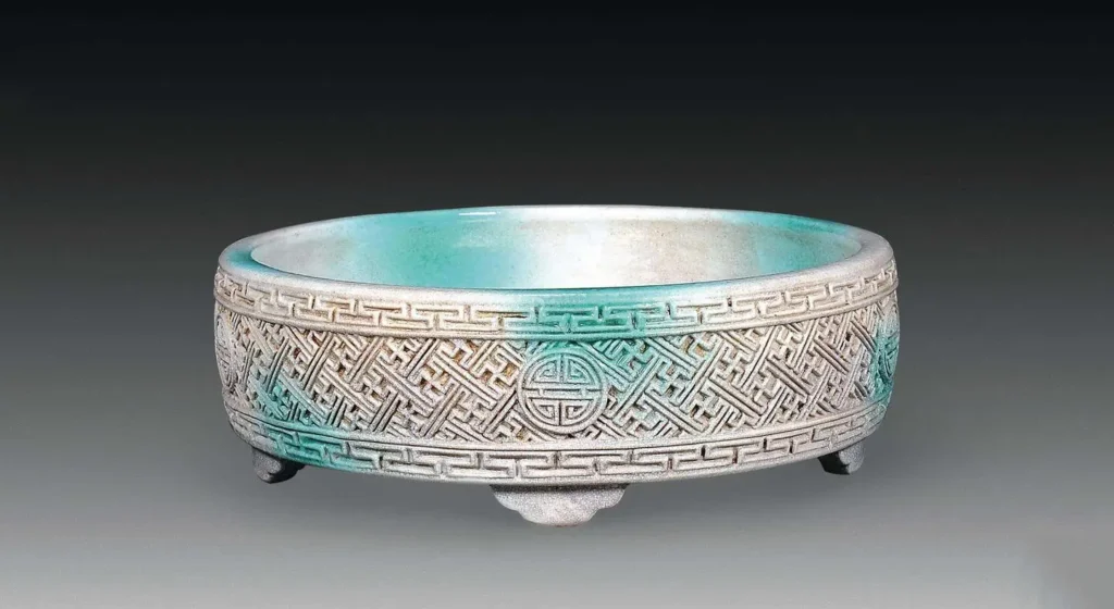 An image of a Qing Dynasty porcelain water-pot decorated with a swastika (Wan character) pattern. The piece features a smooth, evenly applied spray glaze, with the continuous swastika pattern creating a rich, symbolic texture. This exemplifies the sophisticated glaze and decorative techniques of the Qing era.