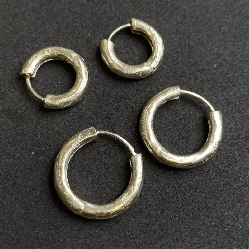 Minimalist handcrafted silver hoop earrings displayed to show fine artisanal details.