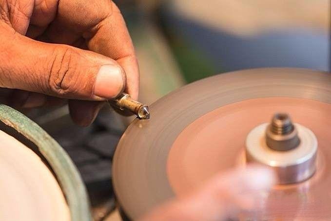 Delicately polishing the waist facets of the gemstone with light pressure to achieve a smooth and even finish
