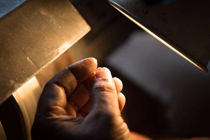 Gemstone cutter inspecting the rough stone to ensure all inclusions and uneven areas are removed before gemstone cutting