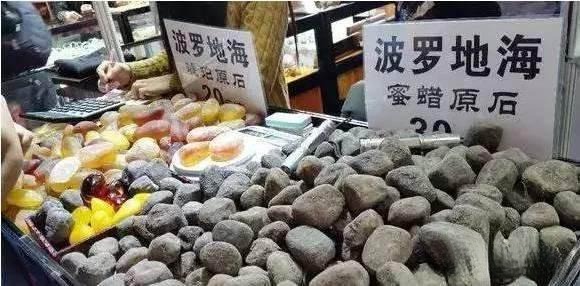 Amber stone being polished live at a market stall, with some pieces made from copal or plastics instead of genuine high-quality amber.