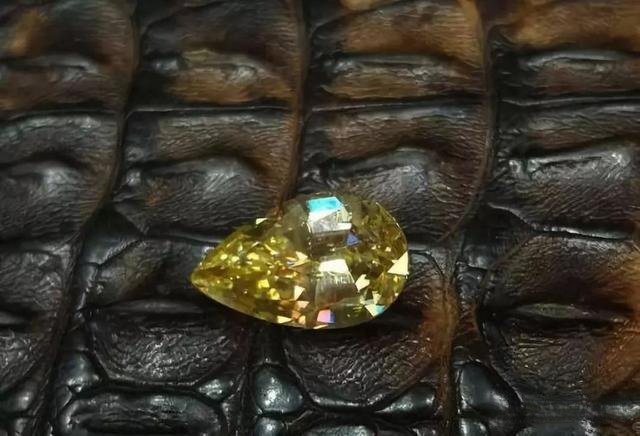 Pear-shaped yellow cassiterite gemstone with bright luster and vivid fire, showcasing its dazzling high-dispersion brilliance