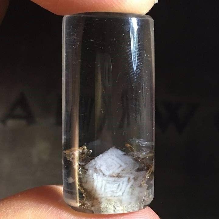 Quartz crystal with concentric and geometric inclusions resembling tree rings, traditional Chinese patterns, and misty mountain landscapes