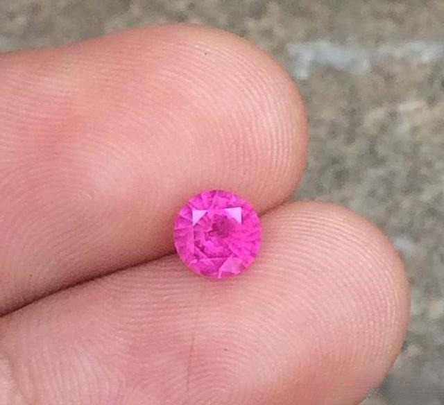 Hand holding a Sri Lankan pink sapphire showing high color saturation, clean and pure tones without gray, brown, or orange undertones
