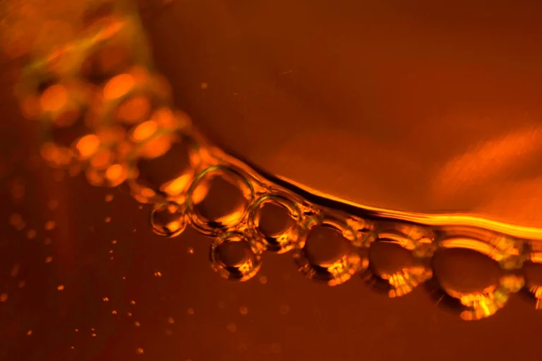 Close-up of vibrant amber liquid with bubbles, serving as the featured background image for Peonyjewels' real amber identification guide.