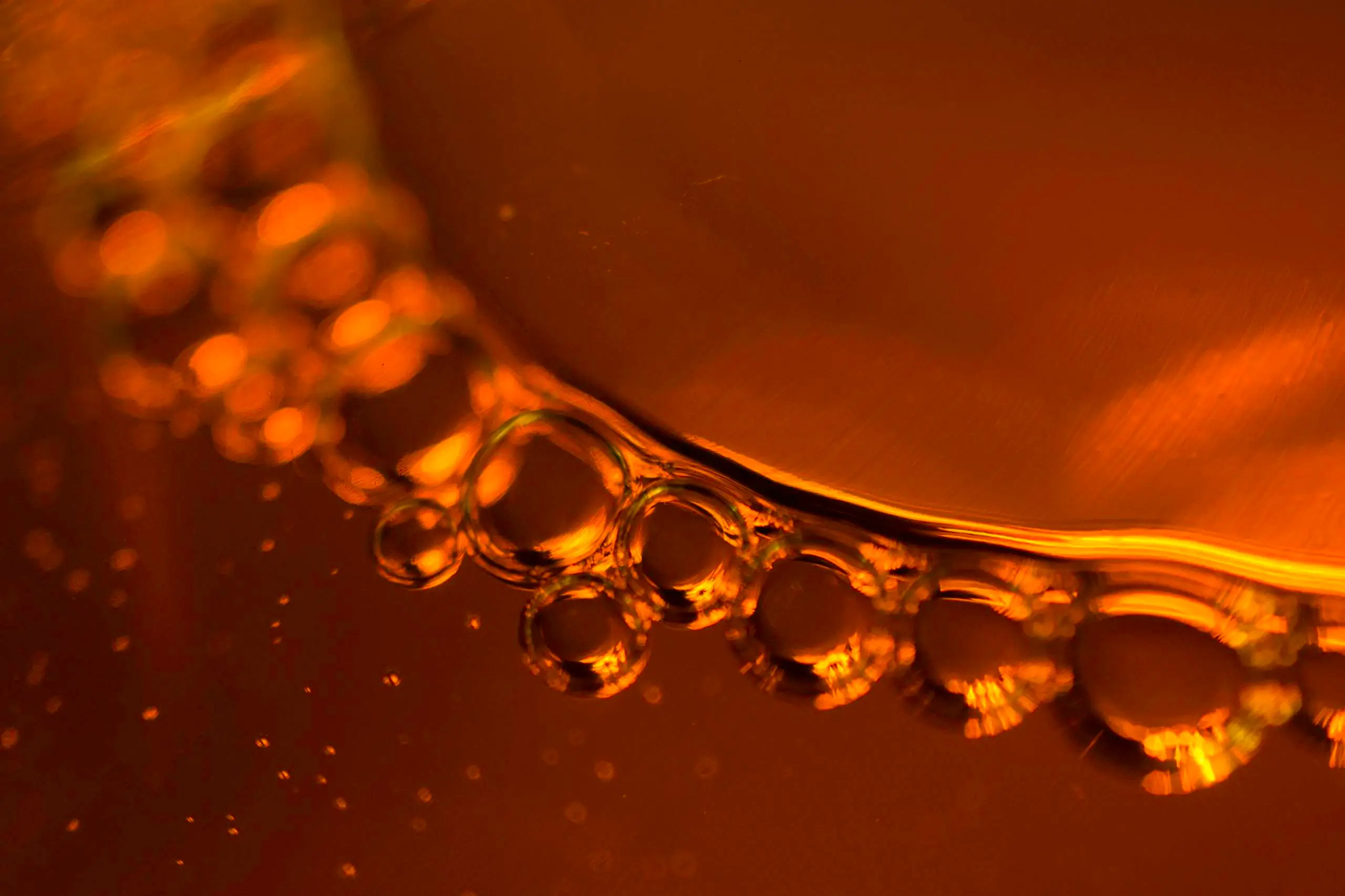 Close-up of vibrant amber liquid with bubbles, serving as the featured background image for Peonyjewels' real amber identification guide.