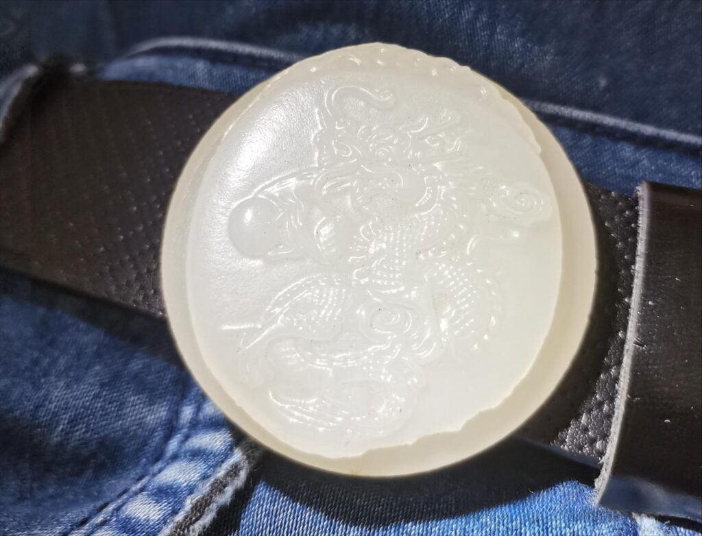 Close-up of an emulsified glass belt buckle made by molding, showing a visible seam line and rounded edges typical of pressed glass.