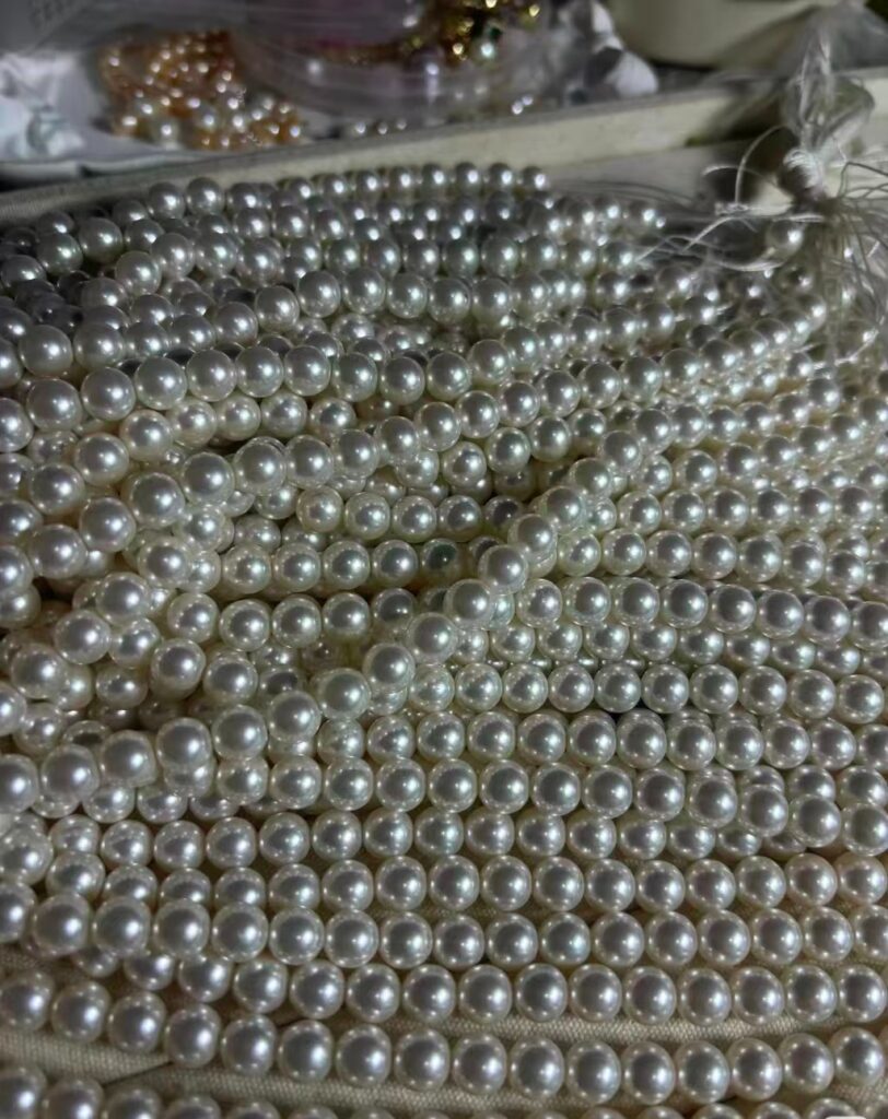 Multiple strands of solid glass faux pearls, displaying smooth, high-luster surfaces and the characteristic heavy feel of dense cores.