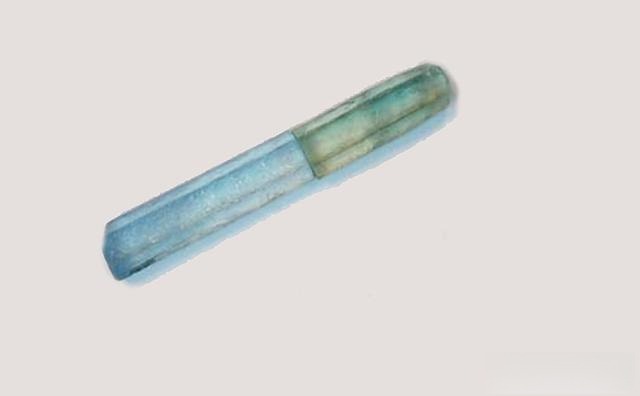 Aquamarine crystal comparison: The top segment shows the natural, untreated pale bluish-green color, while the bottom segment from the same rough displays the enhanced, pure blue color after heat treatment.