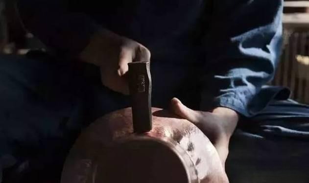 Artisan hammering cut gold sheets into shape using traditional Gu Fa Gold techniques, handcrafted to showcase classic goldsmith craftsmanship
