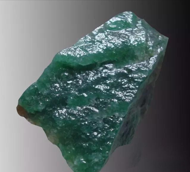 Close-up of a translucent blue-green Nanyang Dushan Jade rough stone, the rarest and highest-value variety.