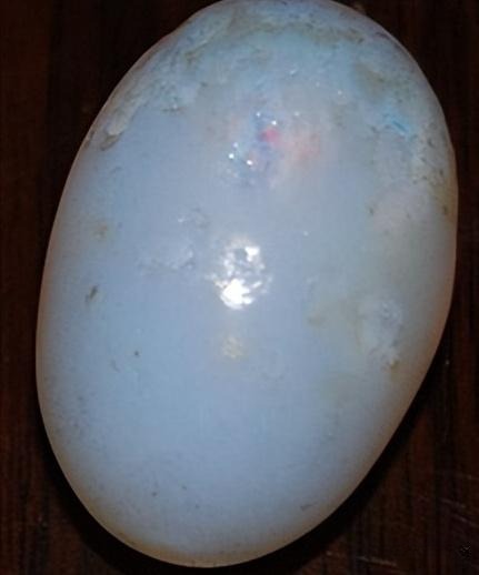 A dull, graying, and lusterless opal with minimal or no play-of-color, demonstrating the significant aesthetic degradation caused by dehydration.