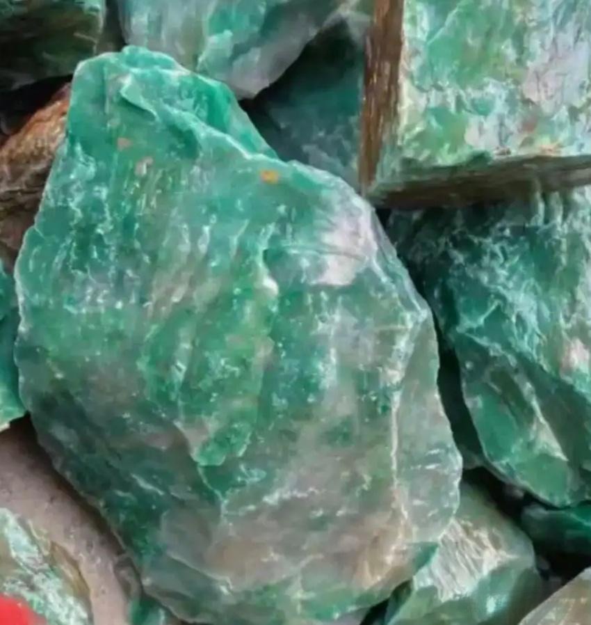 Raw Dulong Jade rough stone showing natural texture and greenish tone before carving or polishing.