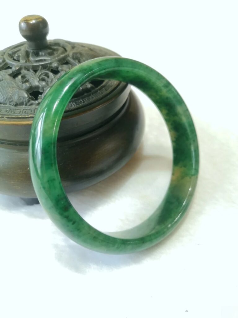 A Dushan Jade bangle displaying the material's characteristic multi-colored appearance, often combining green, white, and brown hues.