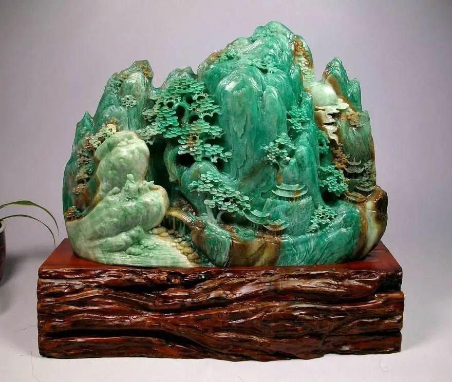 A Dushan Jade carving (mountain landscape) that visually mimics high-grade Jadeite, showcasing mixed white and green color zones and a strong vitreous luster