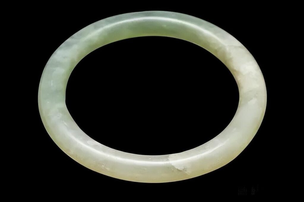 A coarse-textured Serpentine Jade bangle appearing dull and faded due to the loss of adsorbed water from the numerous interstitial pores between the loosely packed antigorite grains.