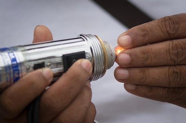 A gem dealer uses a specialized tool light to carefully inspect the quality and clarity of a gemstone, demonstrating the professional evaluation process.