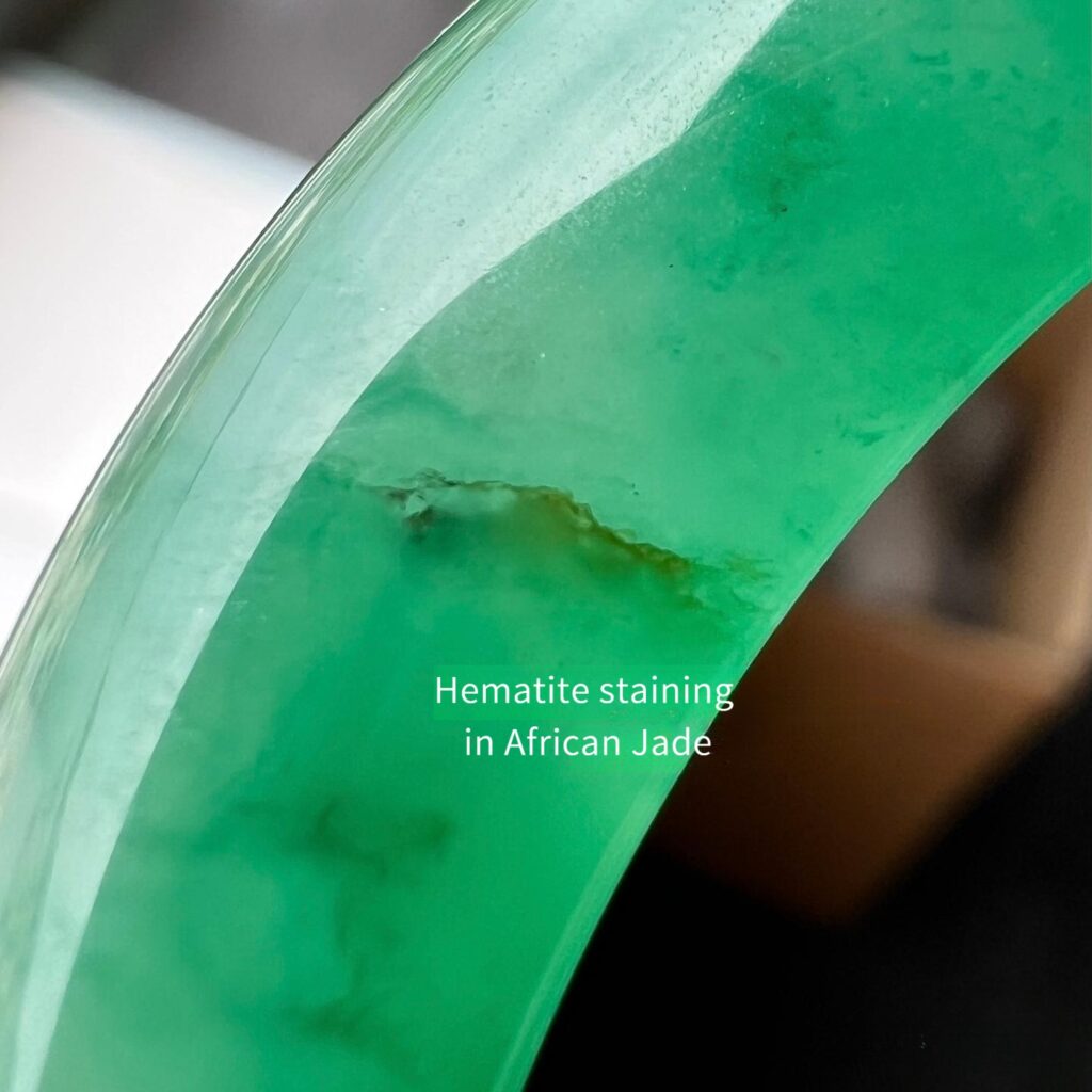 Close-up of a green quartzite bangle showing hematite staining and subtle color variations.