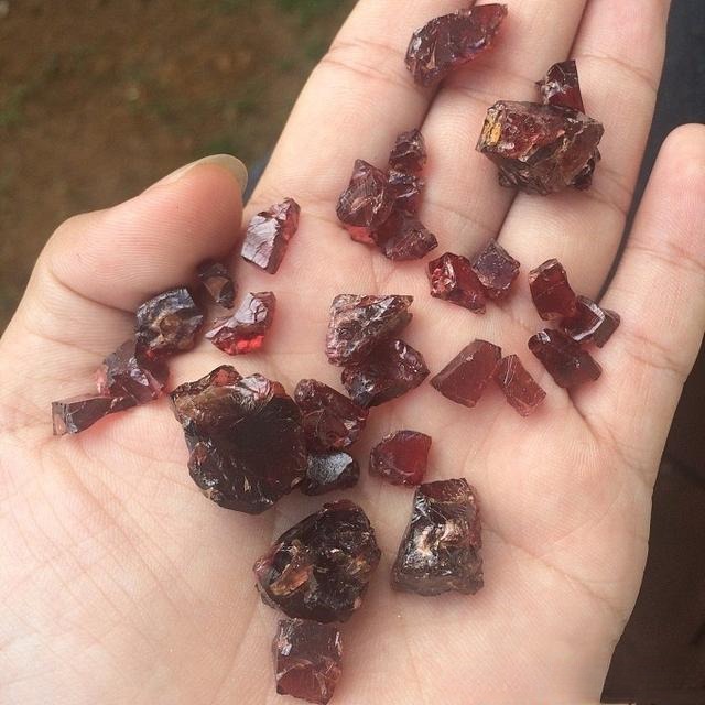 A hand displaying several cut and polished gemstones purchased directly from the Ratnapura gem market in Sri Lanka.