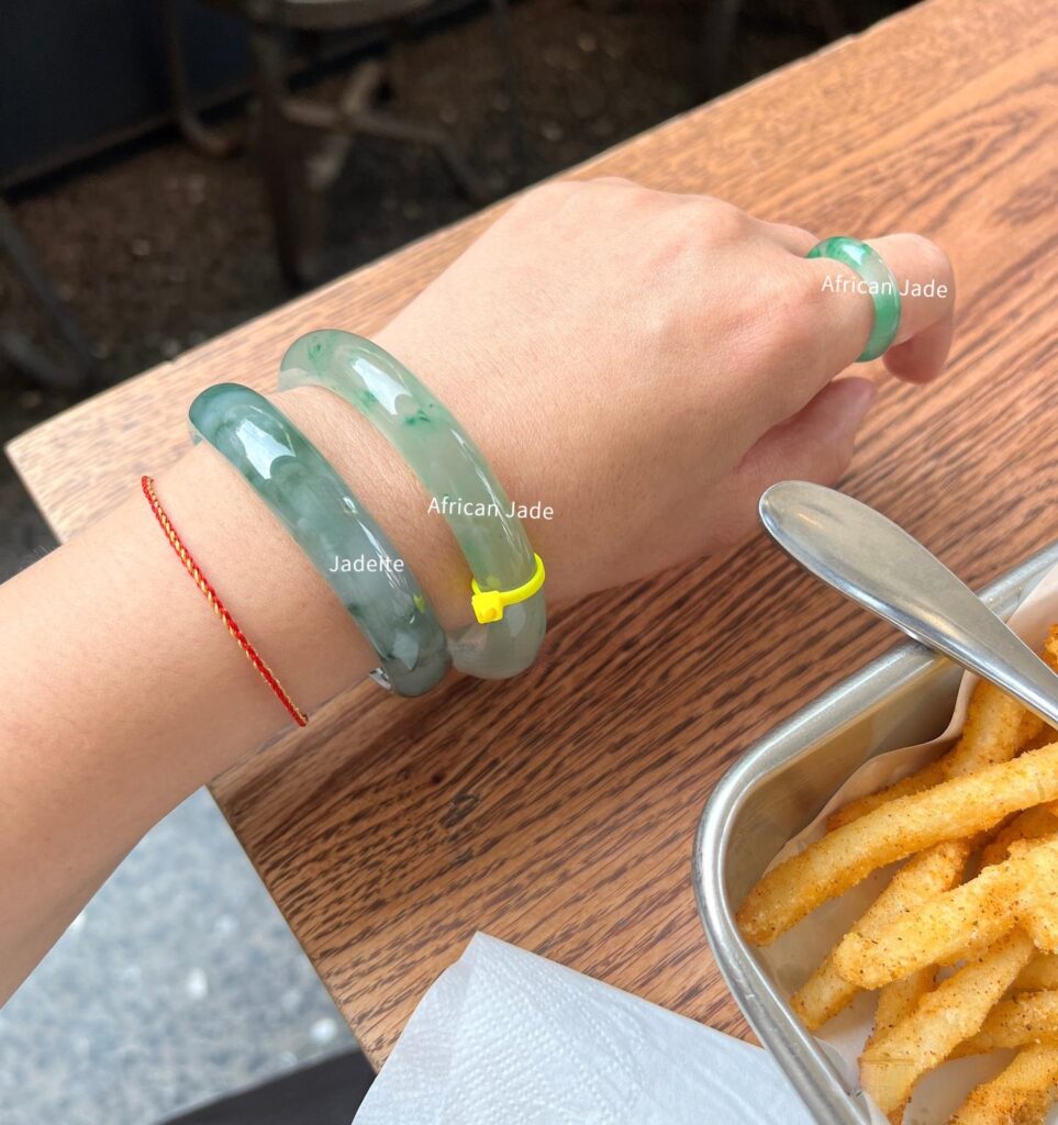 Comparison of a jadeite bangle and an African Jade bangle worn together, highlighting differences in color, translucency, and luster.