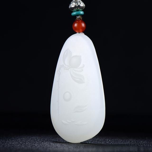 Machine-carved lotus jade pendant with uniform, rigid lines and precise mechanical detailing.