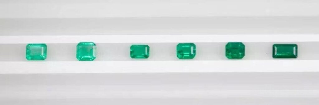 Several side-by-side emeralds from the Muzo mine, displaying a rich and varied spectrum of green hues.