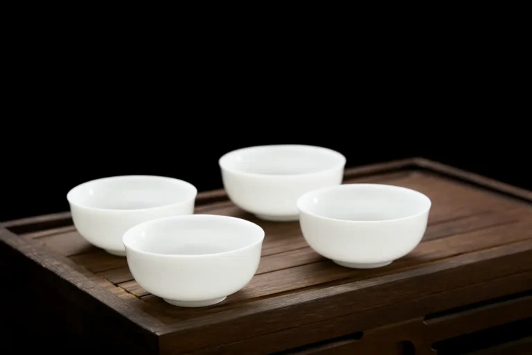Natural mutton fat jade tea cup on black background, highlighting its smooth white texture and elegant craftsmanship.