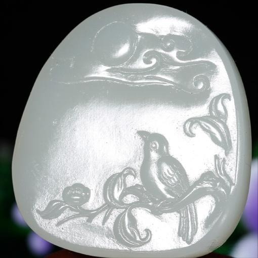Carved Hetian Jade pendant featuring a small bird, highlighting the jade's buttery texture.