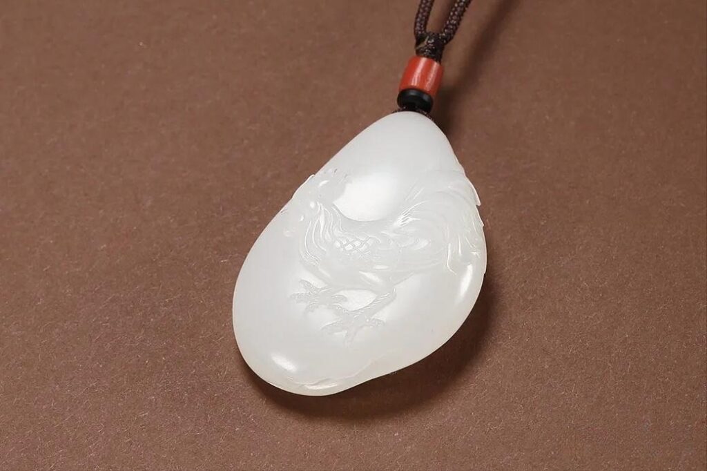 Carved Hetian Jade pendant featuring a rooster (cock), highlighting the jade's smooth texture and finish.