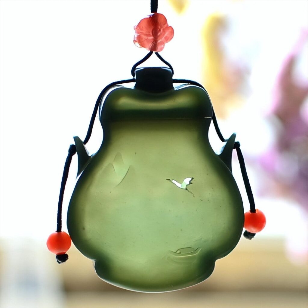 A custom-designed Hetian Celadon Jade (Qingyu) sachet carving from PeonyJewels, showcasing the rare and delicate thin-wall (Bo Tai) carving technique, which achieves exquisite translucency.