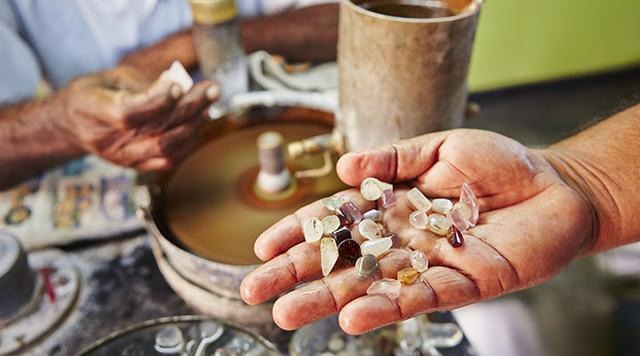 A rough hand displaying various Ceylon Sapphire gemstones, reflecting the decreasing quality and scarcity of top-tier gems due to declining production.