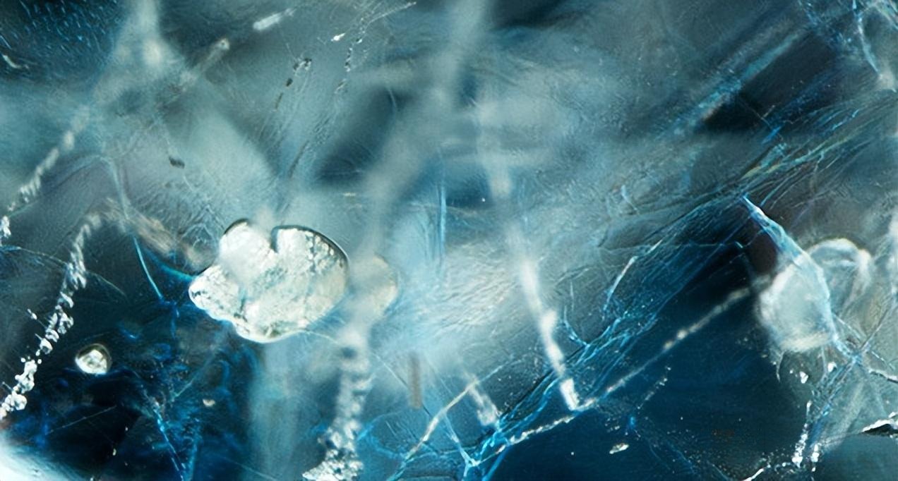 Microscopic view of a sapphire showing flat gas bubbles and the blue flash effect, which are tell-tale signs of extensive lead glass filling.