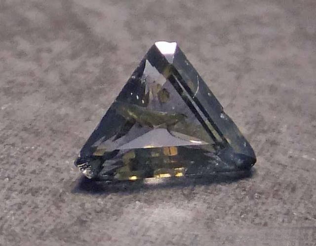 Triangular faceted Fake Sapphire with refractive index 1.701–1.718, showing bluish-green color and clarity