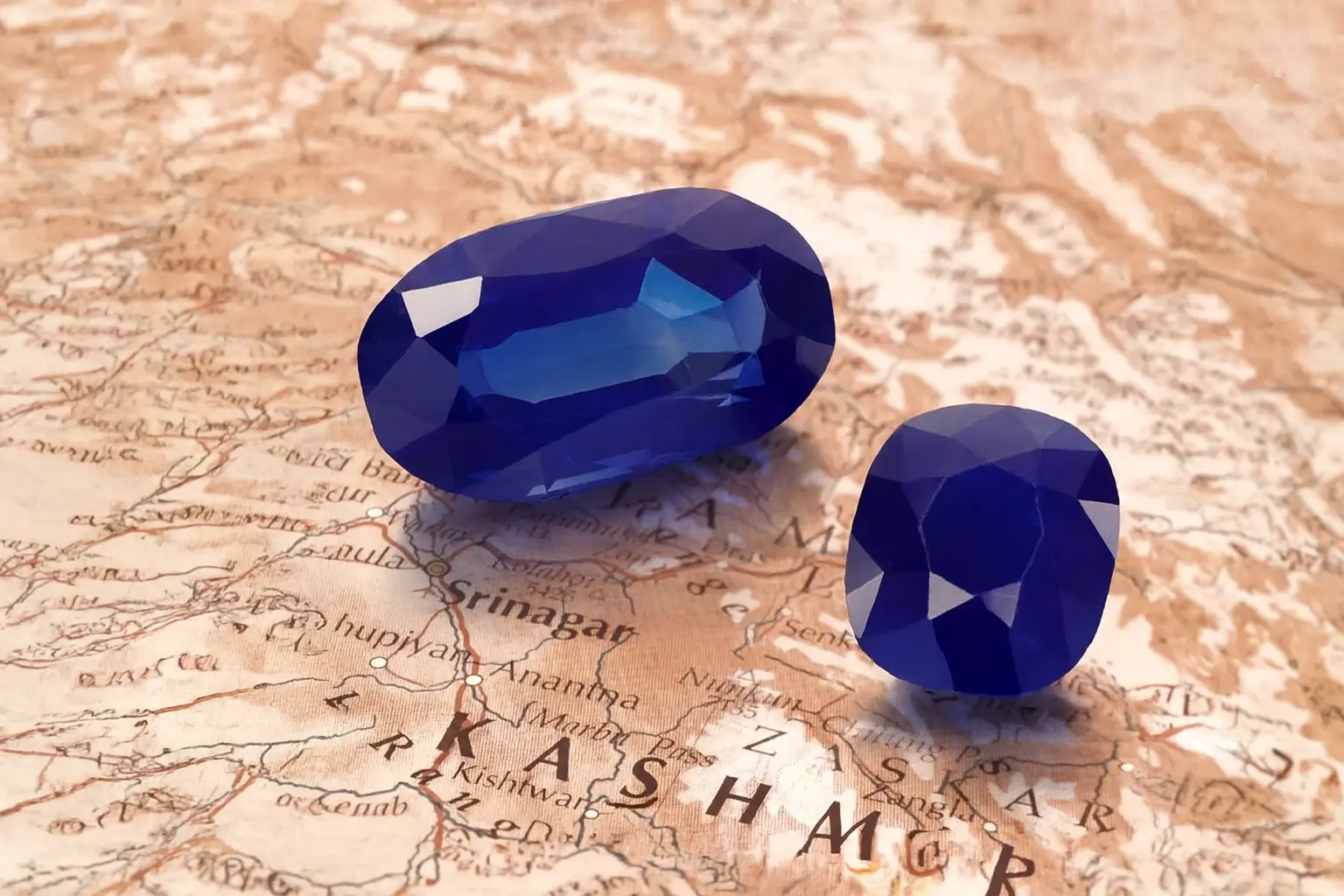 A stunning comparison of two rare Indian specialty gemstones—Kashmir sapphires—weighing 55.19ct and 25.97ct, displaying the signature velvety blue color.