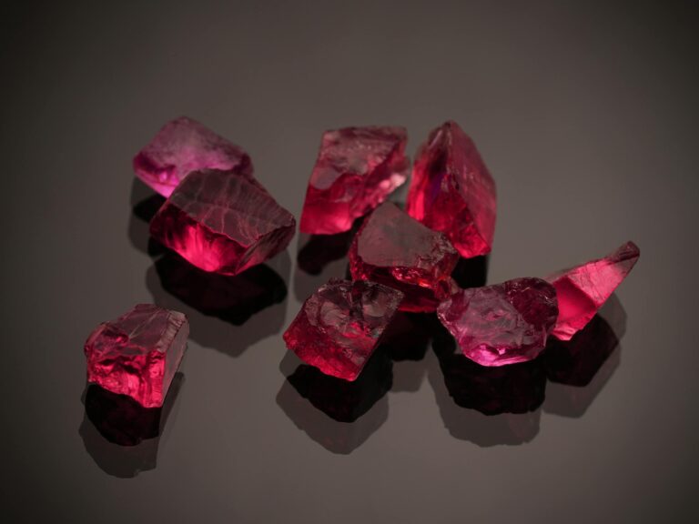 Close-up of vibrant red gemstones on a shiny black surface, highlighting their brilliance and deep color.