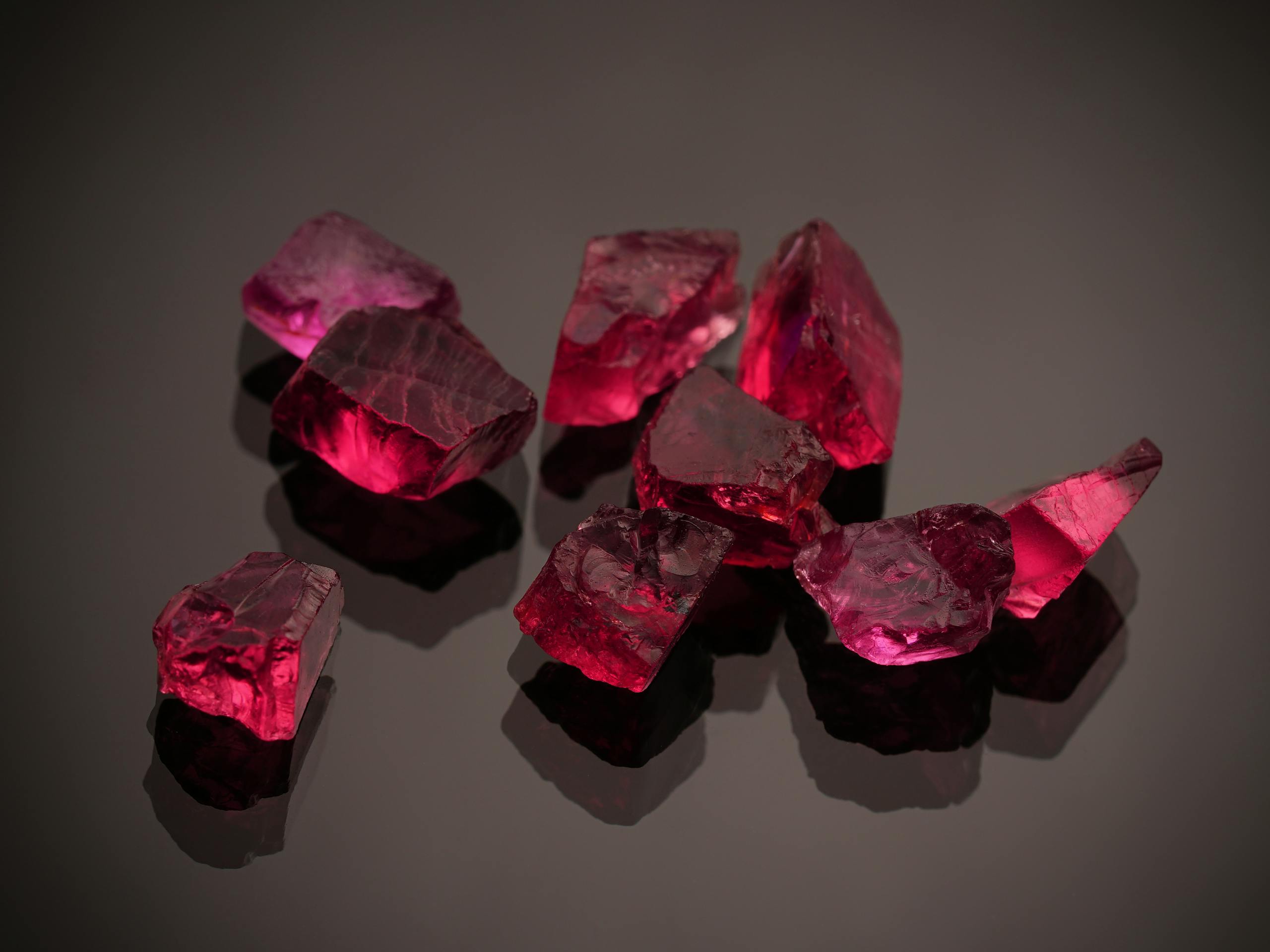 Close-up of vibrant red gemstones on a shiny black surface, highlighting their brilliance and deep color.